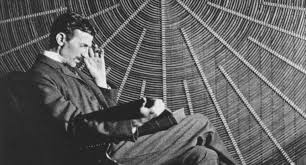 Nikola Tesla sitting in a laboratory surrounded by electrical equipment