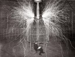 Nikola Tesla sitting in front of a Tesla coil with electrical arcs